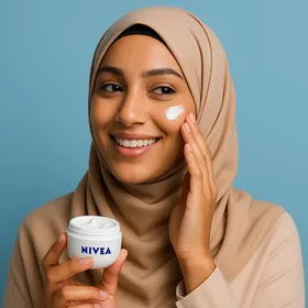 Femme algérienne appliquant crème Nivea sur le visage, fond bleu pastel