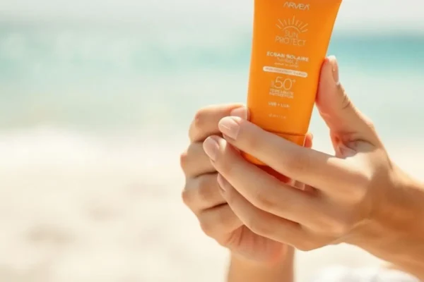 Application de crème solaire fluide sur le visage en Algérie, protection optimale contre le soleil.